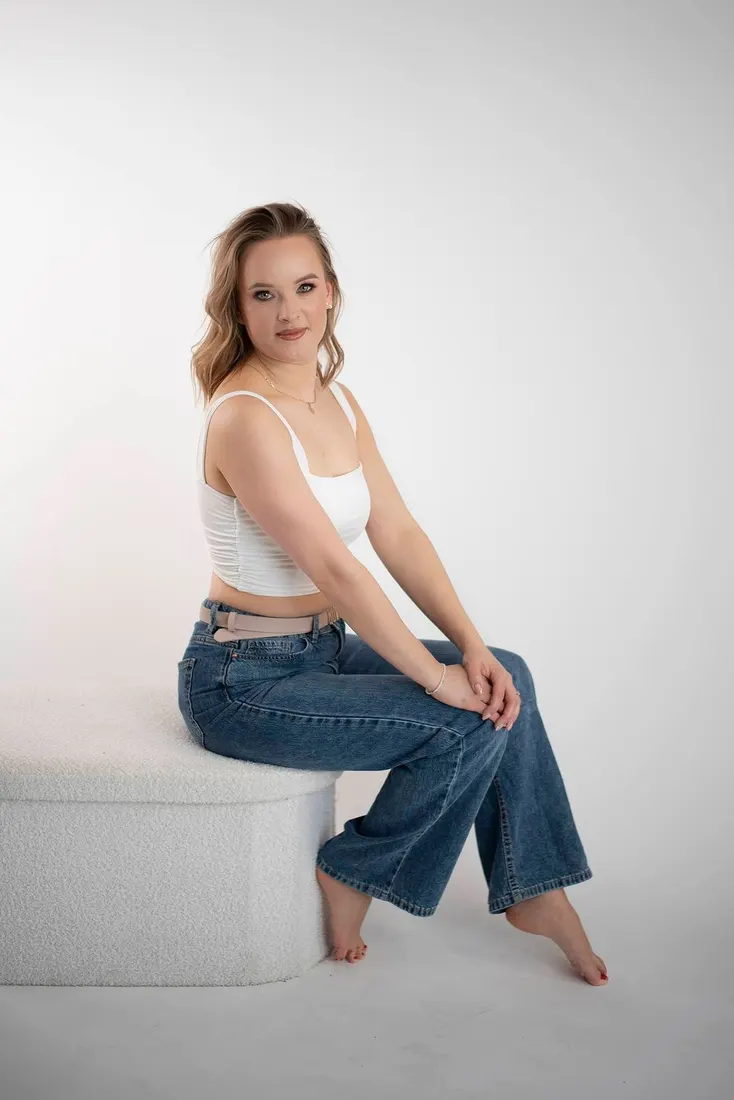 Kobieta w białym topie i jeansach na jasnym tle